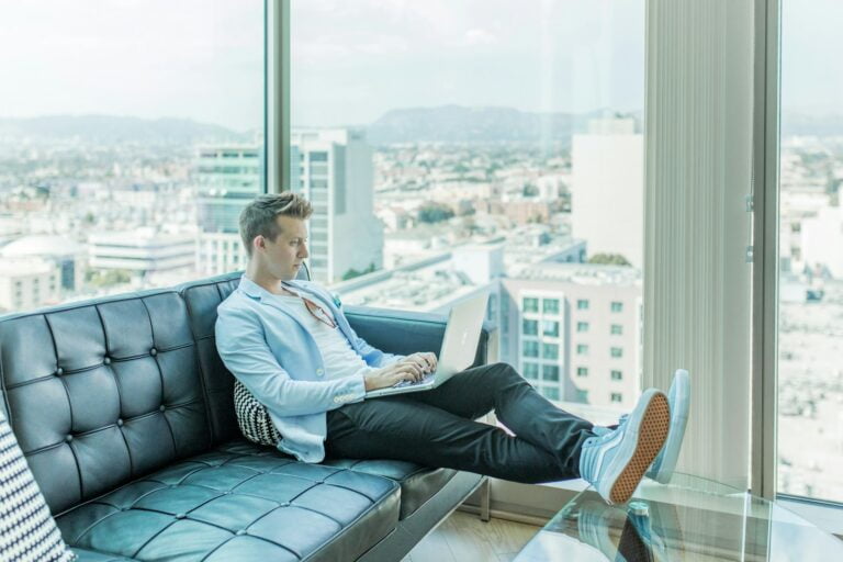 man sitting on sofa while using laptop-Email Marketing Software