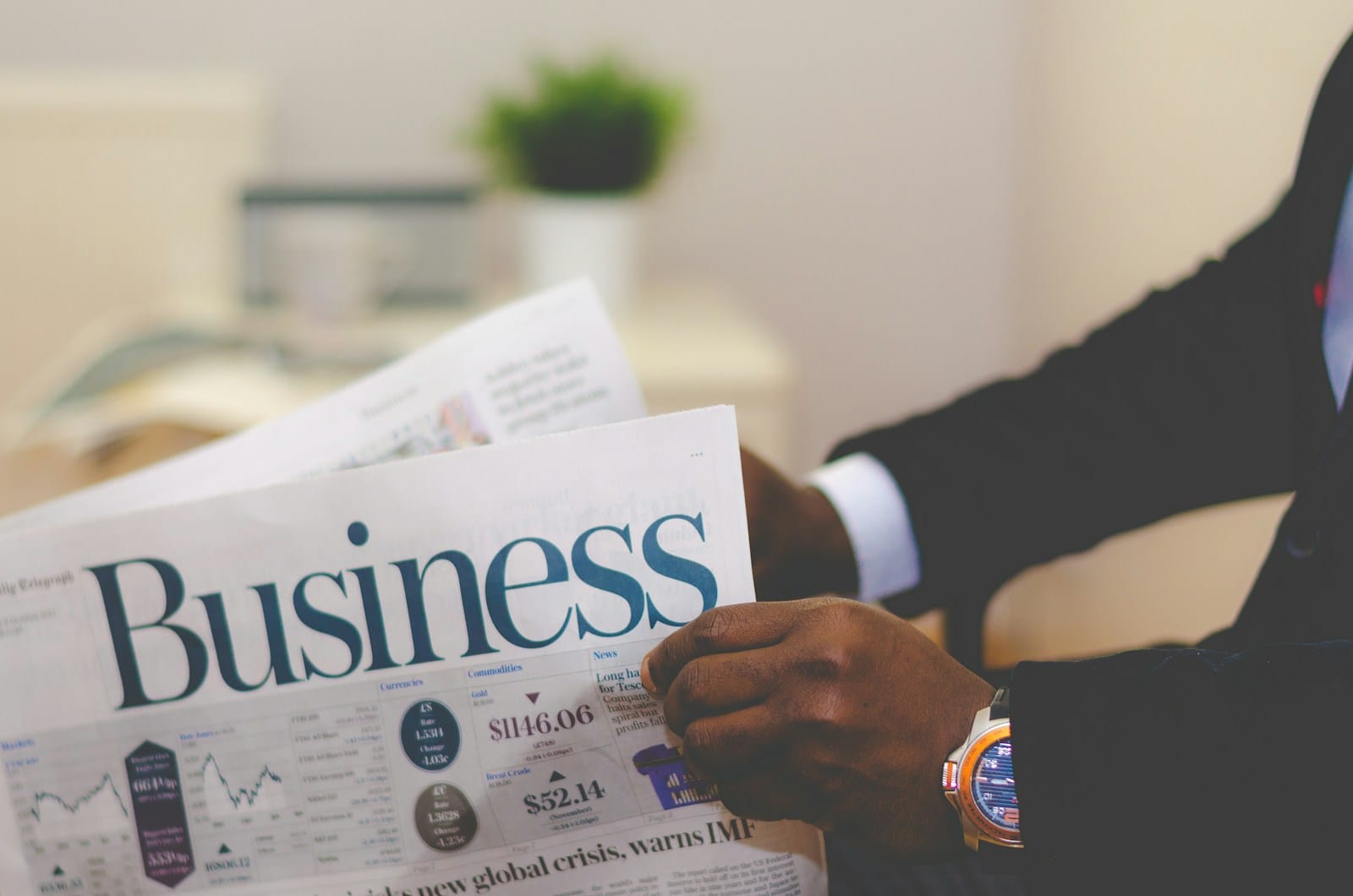 person wearing suit reading business -business email setupnewspaper-