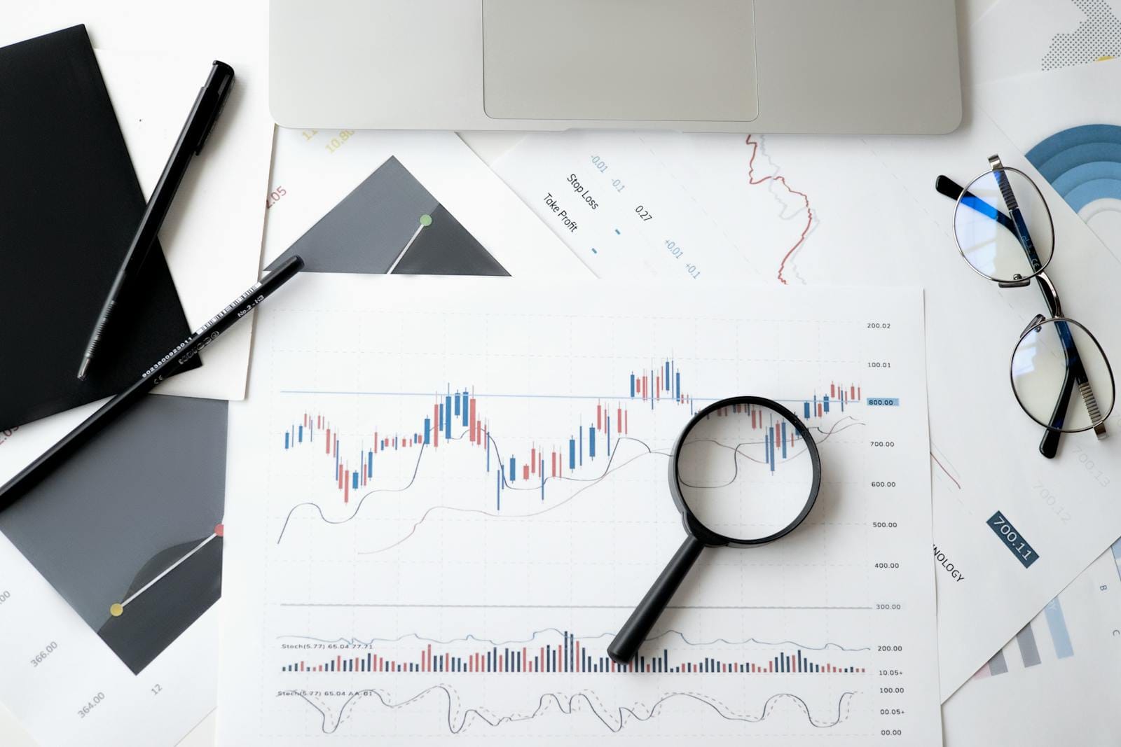 Flat lay of stock market analysis documents with magnifying glass, email marketing analytics